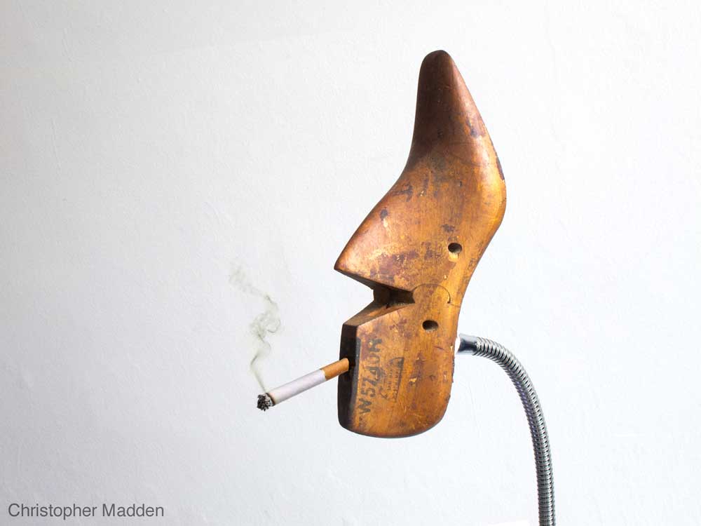 Surrealist contemporary art - shoe last smoking cigarette Surrealist dada contemporary sculpture involvinng pareidolia - cigarette and shoe last